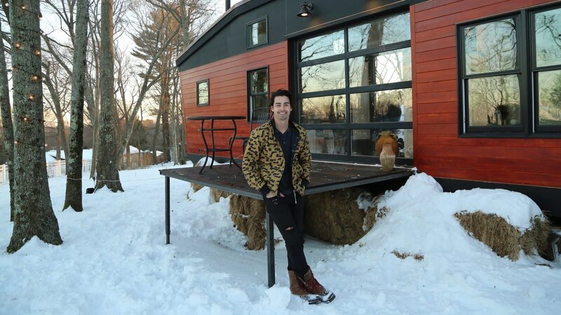 Tiny house builder and owner Sterling Folkestad leans alongside the patio with a huge smile on his face as he cannot believe he is here with his friends and family celebrating the end of this build, as seen on Tiny House, Big Living. – Bild: DIY Network/​Scripps Networks, LLC.