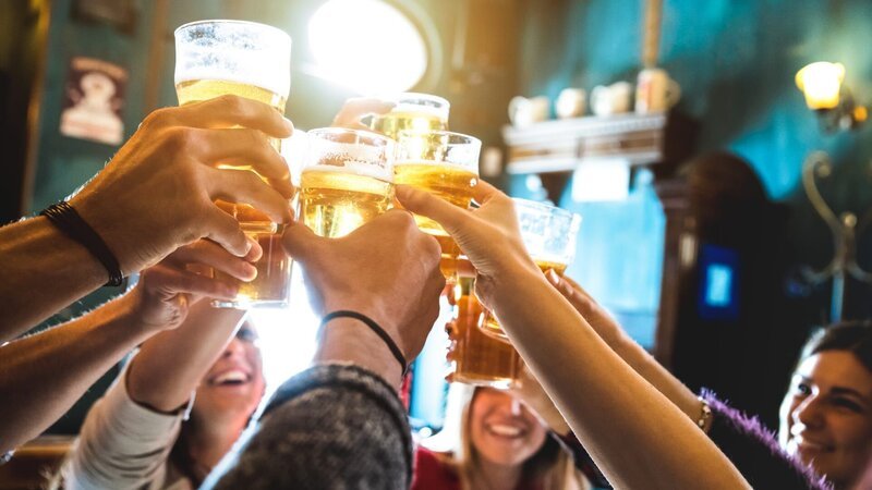 Group of happy friends drinking and toasting beer at brewery bar restaurant – Friendship concept with young people having fun together at cool vintage pub – Focus on middle pint glass – High iso image – Bild: ViewApart /​ Getty Images/​iStockphoto /​ iStockphoto