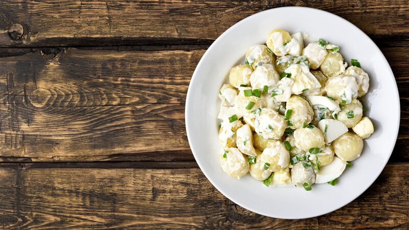 Potato salad with eggs and green onion on white plate over wooden background with copy space. Top view, flat lay food – Bild: Tatiana Volgutova