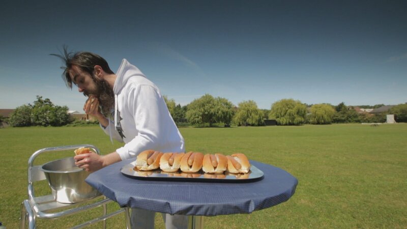 LONDON – Adam is walking his dog and comes across an all you can eat hot dog buffet. The vendor has fifteen hot dogs left but only five minutes until he closes, Adam takes the challenge to eat all fifteen hot dogs in five minutes. – Bild: The National Geographic Channel