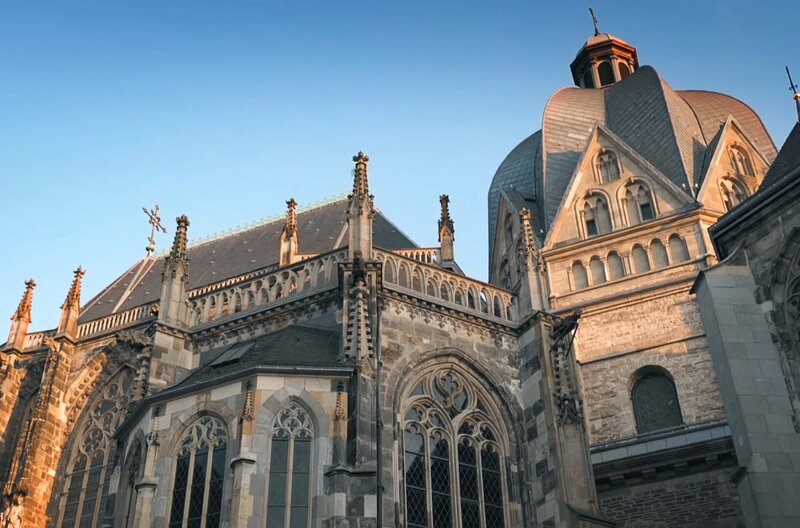 Die prachtvolle Außenansicht des Aachener Doms im Abendlicht: Der Dom überstand Kriege und Brände. – Bild: Marcus Winterbauer /​ © Marcus Winterbauer