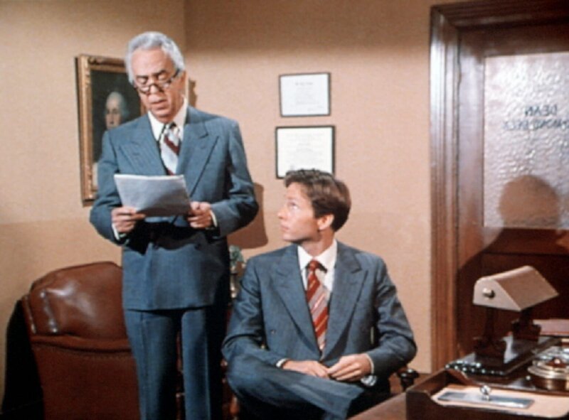 Dean Beck (Ivor Francis, l.) studiert einen Programmvorschlag von John Boy (Robert Wightman, r.), der sich damit an der Boatwright-Universität bewirbt. – Bild: WARNER BROS. INTERNATIONAL TELEVISION