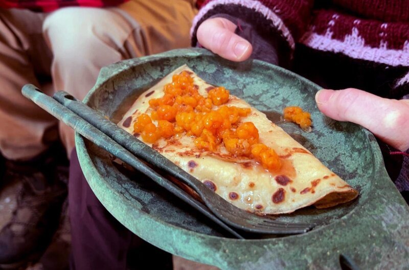 Im lappländischen Ylläsjärvi backt Anja Pfannkuchen in einem Tipi über dem Holzfeuer. Serviert werden diese mit Fichtensirup und arktischen Brombeeren. – Bild: Elephant Doc