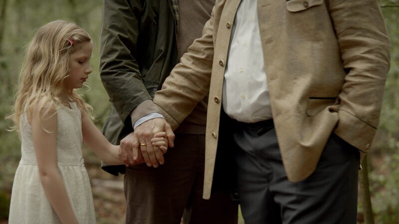 Von links: Die kleine Lucy (Carlotta von Falkenhayn ) wird im Wald von Kai Voss (Sebastian Hülk) an Frank Wilhelm (Michael A. Grimm) übergeben. – Bild: ZDF und BR/​Wiedemann & Berg Television GmbH & Co