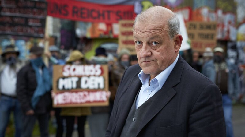 Georg Wilsberg (Leonard Lansink) unter falscher Identität als finanzstarker Investor bei einer Demonstration der Freihafen Initiative Münster. – Bild: ZDF und Guido Engels