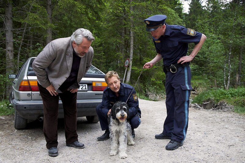 Nachdem der Trüffelhund des Verstorbenen herrenlos durch den Wald gelaufen ist, nehmen sich Kommissar Stadler (Dieter Fischer, l.), Polizeihauptmeister Mohr (Max Müller, m.) und dessen Kollege seiner an. – Bild: ZDF