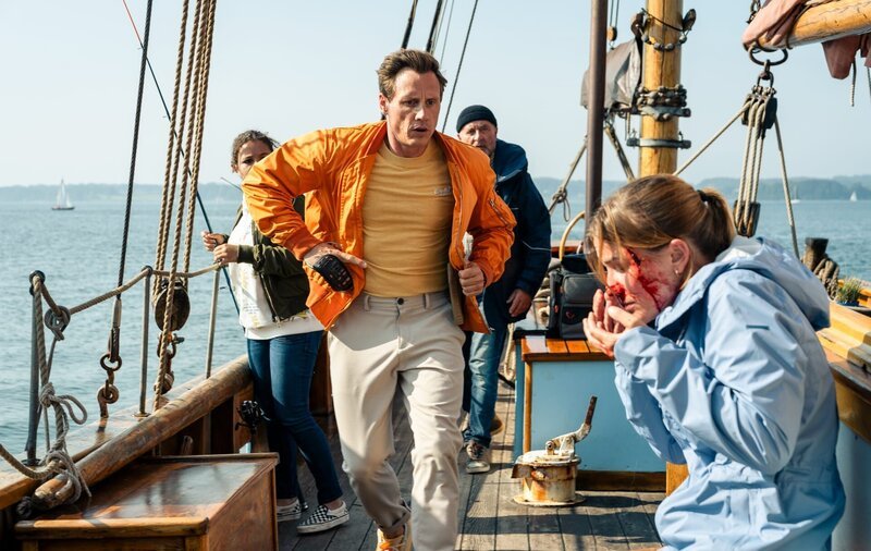 Moritz Neiss (Patrick Kalupa, M.) rennt zu Mimi (Lea Freund, r.), der ein schlecht geworfener Angelhaken das Gesicht schwer verletzt hat. – Bild: ZDF