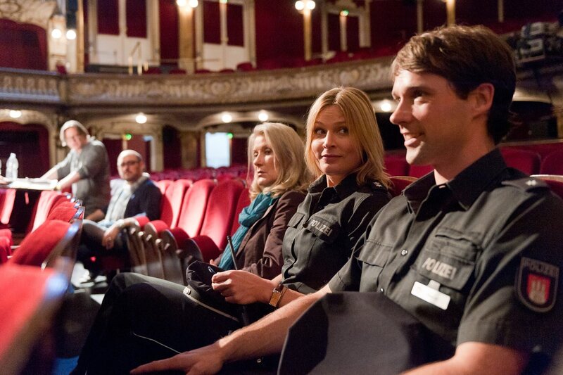 Mattes (Matthias Schloo, r.) ist amüsiert darüber, dass Melanie (Sanna Englund, 2.v.r.) mit ihrem Handyklingeln den Zorn des Theaterregisseurs Harting (Hannes Hellmann, l.) und seines Assistenten (Gabriel Munoz Munoz, 2.v.l.) auf sich gezogen hat. Dabei hatte die Assistentin der Intendanz (Hedi Kriegeskotte, M.) sie vorgewarnt. – Bild: ZDF und Boris Laewen