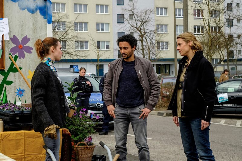 Die Kommissarin Tamara Meurer (Anja Pahl, r.) und ihr Kollege David Grünbaum (Omar El-Saeidi, M.) befragen die Nachbarin der Toten, Melina Satori (Victoria Schulz, l.). Sie haben sich gemeinsam um das Gemeinschaftsbeet in der trostlosen Hochhaussiedlung gekümmert. – Bild: ZDF