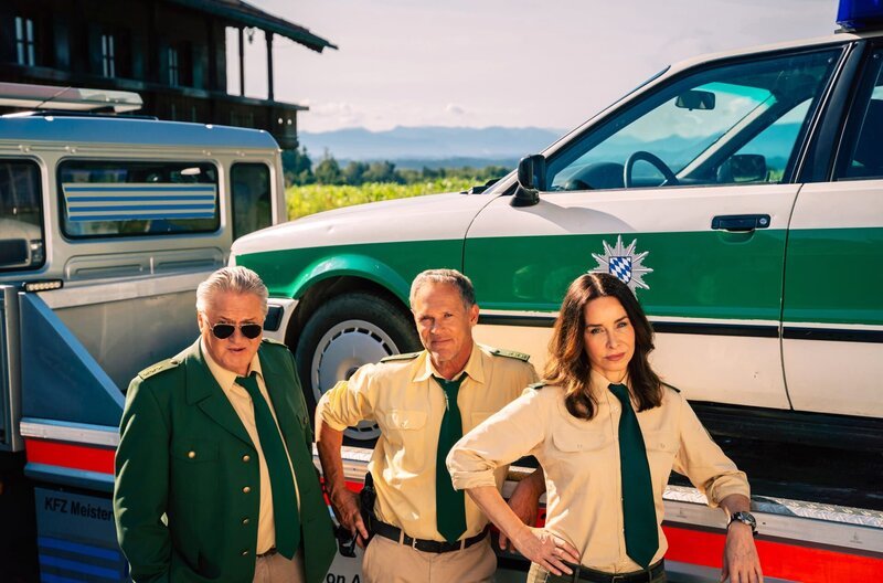 ARD HUBERT OHNE STALLER, 10. Staffel mit 16 neuen Folgen voraussichtlich ab immer mittwochs um 18:50 Uhr im Ersten. Hubert ohne Staller – 10 Jahre – 10 Staffeln Auf dem Land ticken die Uhren anders, und Recht haben die Leut’, in Wolfratshausen ticken die Uhren aber noch einmal in einem ganz anderen Takt: im „Hubert ohne Staller“-Takt. Und der gerät manchmal aus dem Takt, denn die Ermittlungsmethoden der Polizei sind ein bisschen ungewöhnlicher als anderswo, – sagen wir mal – nicht ganz nach den Richtlinien des Gesetzes. Aber: Auf dieses etwas unorthodoxe Uhrwerk ist Verlass – und zwar seit 10 Jahren! Herzlichen Glückwunsch – oder wie man in Bayern so schön sagt „passt scho“! Dieses Polizeirevier in Wolfratshausen ist nicht zu unterschätzen – und auch wenn jeder mittlerweile die Protagonisten kennt, sollte man sie an dieser Stelle noch einmal vorstellen: V.l.n.r. Reimund Girwidz (Michael Brandner), Franz Hubert (Christian Tramitz), Sabine Kaiser (Katharina Müller-Elmau) – Bild: ARD/​TMG/​Jenrick Mielke