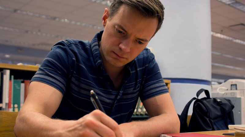 Adam Berry takes notes during a research scene. – Bild: Discovery Communications