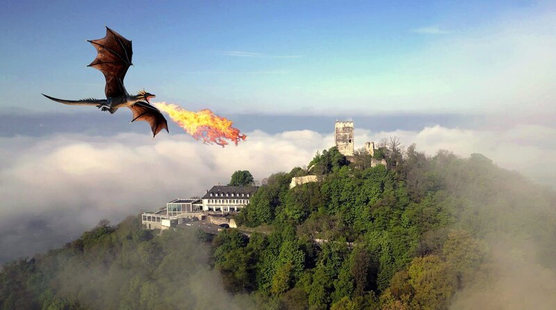  Ein feuerspeiender Drache (KI-generiert) über dem Drachenfels, der sich im Morgennebel über dem Rheintal erhebt. Der Mythos vom Fabelwesen regt bis heute die Fantasie der Besucher an und macht einen Großteil der Anziehungskraft des Berges aus.  – Bild: WDR
