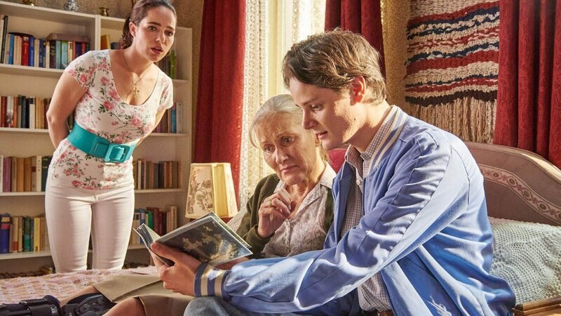 Waltraud (Hedi Kriegeskotte, M.) hat Besuch von ihrem charmanten Verwandten Karl (Johannes Franke) bekommen. Er zeigt ihr die Gräber ihrer Vorfahren, um die sich Karl liebevoll kümmert. Magda (Verena Altenberger) verfolgt das Gespräch interessiert. – Bild: TVNOW /​ Reiner Bajo