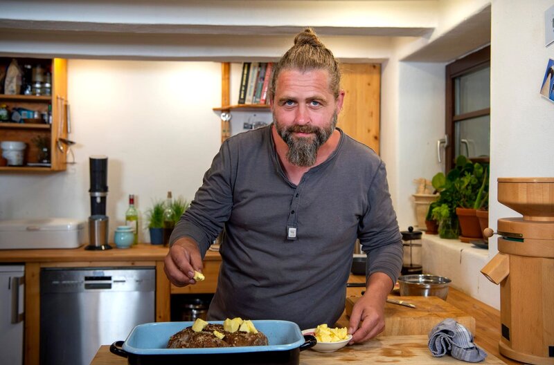 Gastgeber Sebastian Klein bereitet für sein Menü eine Lammschulter mit Honig-Knoblauch-Kruste zu. – Bild: WDR/​Melanie Grande