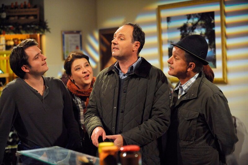 Die Lansinger machen sich über Huberts Quiz-Teilnahme lustig. Von links: Florian Brunner (Tommy Schwimmer), Monika Vogl (Christine Reimer), Hubert Kirchleitner (Bernhard Ulrich) und Bürgermeister Schattenhofer (Werner Rom). – Bild: BR/​Marco Orlando Pichler