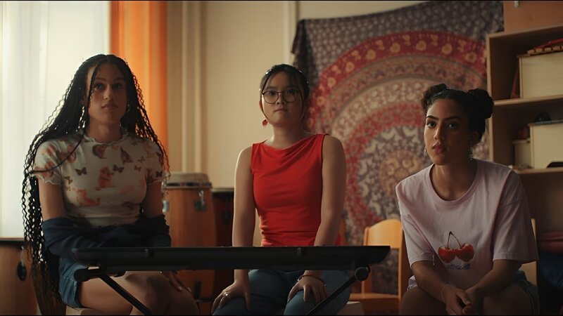 Châu (Ngoc Nhi Ha Tran, Mitte) hat einen fragwürdigen Plan, wie sie endlich die Melodie für das Bandstück perfekt vorführen kann. Dafür braucht sie die Hilfe der beiden älteren Schulkameradinnen Julia (Claire Nae Lienshöft, links) und Alina (Imane Lahna, rechts) aus der Musik-AG. – Bild: ZDF/​ Studio Zentral