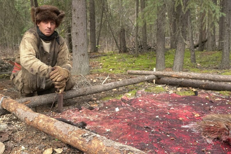 Oliver kneeling next to moose hide. – Bild: Discovery Channel /​ Discovery Communications, LLC