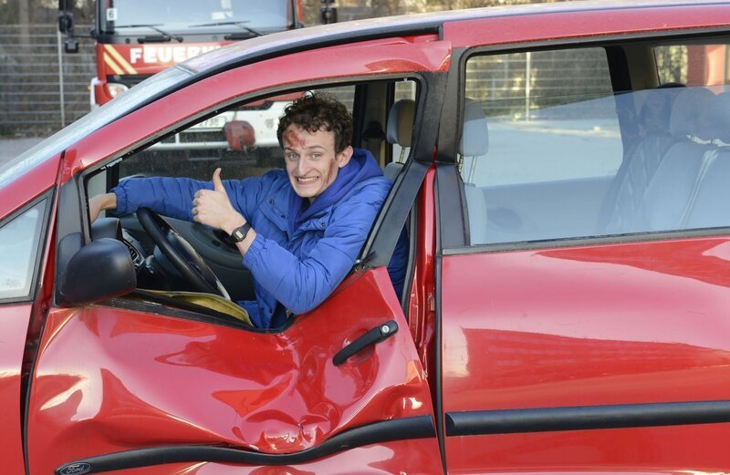 Julian spielt den Verletzten und lässt sich aus einem Auto retten. – Bild: BR/​megaherz gmbh/​Martin Huber