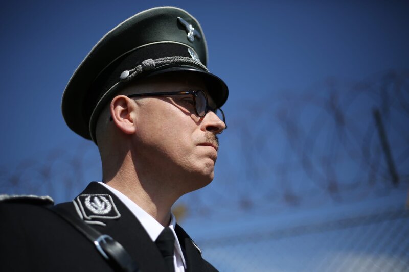 RE-CREATION – Himmler comes to inspect the Dachau camp and stands with barbed wire fence behind him. – Bild: DSP tv /​ Mikolaj Bakalarz /​ National Geographic Channels