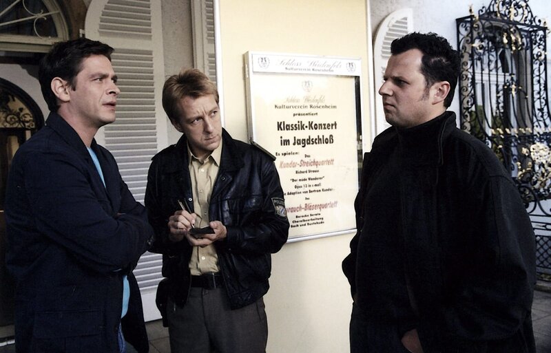 Der tote Geiger beeindruckt den Trompeter Helmut Weyrauch (Gerhard Wittmann, r.) wenig und entsprechend unwillig beantwortet er die Fragen von Rosenheim-Cop Christian Lind (Tom Mikulla, l.) und Michi Mohr (Max Müller). – Bild: ORF