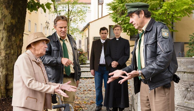 Hubert (Christian Tramitz, 2. von links) und Staller (Helmfried von Lüttichau, rechts) überprüfen eine alte Dame (Lilo Kriechel, links). Ist sie die Opferstock-Diebin? Im Hintergrund: Martin Riedl (Paul Sedlmeir, 3. von links) mit Pfarrer Franz Reich (Thorsten Krohn). – Bild: ARD/​TMG/​Arvid Uhlig