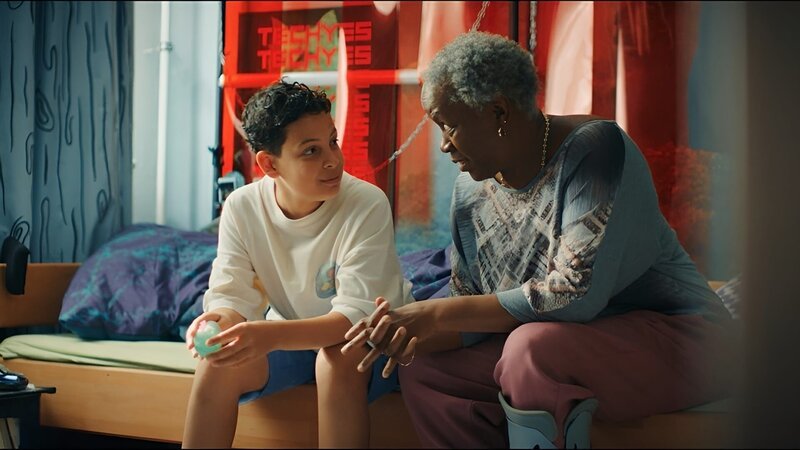 Tom (Noah Bailey, links) vertraut seinen Liebeskummer seiner Oma Senait (Robin Gooch, rechts) an, und die Oma bittet Tom, ihr bei der Wohnungssuche zu helfen. – Bild: ZDF/​ Studio Zentral