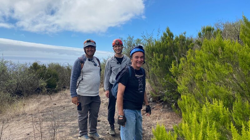 Moderator Eric Mayer (M.) ist mit Vulkanexperte Jaime Colleo (l.) und Biologe Rafael Garcia Becerra (r.) auf La Palma auf dem Weg in eine Lavaröhre. Dort wollen sie schauen, welche Insekten sich entwickelt haben und generell, wie eine Lavaröhre von innen aussieht und welche Spuren des Lavaflusses dort zu erkennen sind. – Bild: ZDF und Sandra Palm