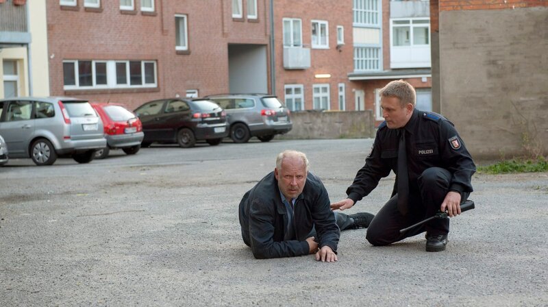 Nach einem Brand in seiner Wohnung schleppt sich Borowski (Axel Milberg, li.) auf die Straße. Die Kollegen tippen auf einen Molotov-Cocktail, den jemand in seiner Wohnung entzündet hat. – Bild: NDR/​Christine Schroeder