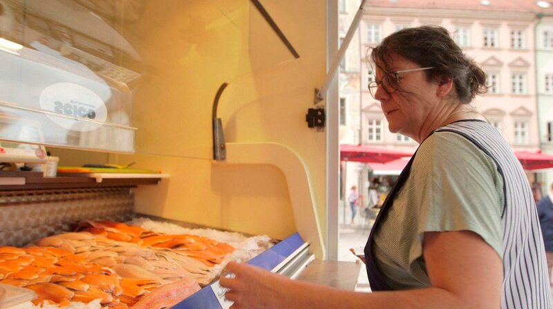 Susanne Sanktjohanser legt die frischen Fische, aus der eigenen Fischzucht, auf dem Markt in Landsberg am Lech aus. – Bild: BR/​Sandra Schlittenhardt