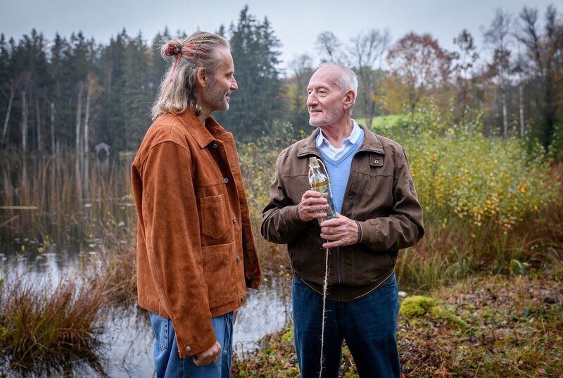 Alfons (Sepp Schauer, r., mit Erich Altenkopf) deponiert die Flaschenpost, damit Hildegard sie finden kann. – Bild: ARD/​WDR/​Christof Arnold