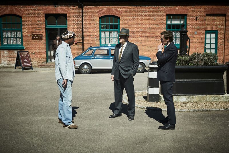 Die Ermittlungen führen Inspektor Morse (Shaun Evans, r.) und seinen Partner Fred Thursday (Roger Allam, M.) zu einem nahegelegenen Taxistand. Der Taxifahrer Clarry Hynes (Fraser James, l.) wird bei dieser Gelegenheit zu seiner Verbindung mit dem Mordopfer befragt. – Bild: ZDF