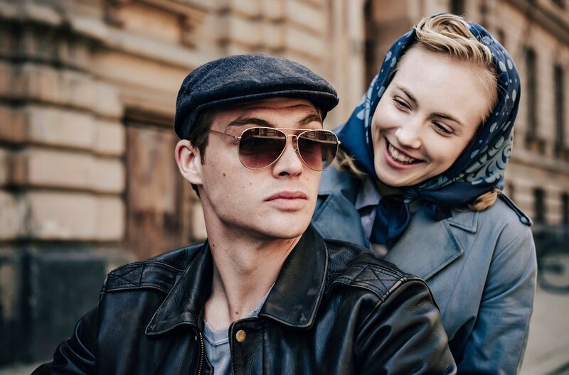 Ulla Wolf (Elisa Schlott) strahlt Tommy Weidner (David Schütter) an, als sie hinter ihm auf dem Motorrad sitzt. – Bild: HR/​WDR/​UFA Fiction/​Willi Weber