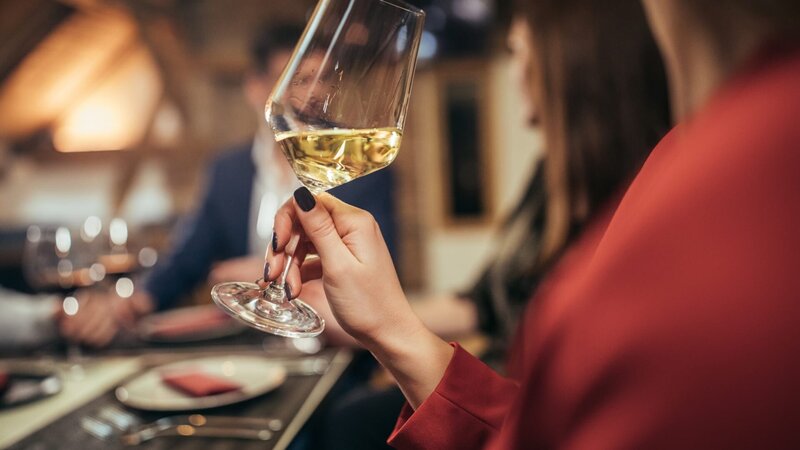 Group of people, men and women, sitting in restaurant together, woman holding wineglass. – Bild: South_agency /​ Getty Images/​iStockphoto