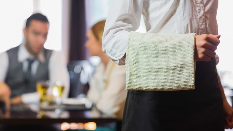 Waitress standing in front of two business people talking in a restaurant – Bild: Wavebreakmedia /​ Getty Images/​iStockphoto