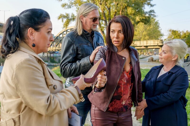 Gerichtsmedizinerin Dr. Franziska Beck (Maria Happel, l.) klärt Carl Ribarski (Stefan Jürgens, 2. v. l.) und Dr. Henriette Wolf (Brigitte Kren, r.) auf: Der Abdruck auf dem Ermordeten kam von Nadia Blascheggs (Sandra Cervik, 3. v. l.) Stöckelschuh. – Bild: ORF/​Satel Film/​Petro Domenigg