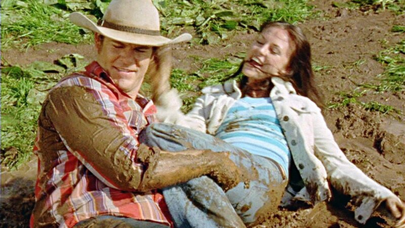 Alex (Aaron Jeffery) und Fiona (Michelle Langstone) wälzen sich glücklich im Schlamm. – Bild: TVNOW