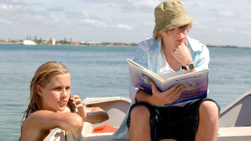 Lewis (Angus McLaren, l.) studiert ein Buch mit mystischen Seewesen, während Emma (Claire Holt, r.) als Meerjungfrau im Meer unterwegs ist. – Bild: ZDF
