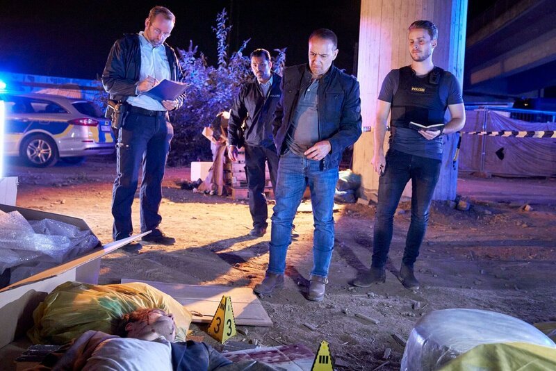 Max (Nicolas Wolf, r.) und Semir (Erdogan Atalay, 2.v.r.) sind bei eine unidentifizierte männliche Leiche auf einer Autobahnbaustelle. Max konfrontiert Semir dabei mit Fragen zu Semirs Vergangenheit. – Bild: RTL /​ Guido Engels