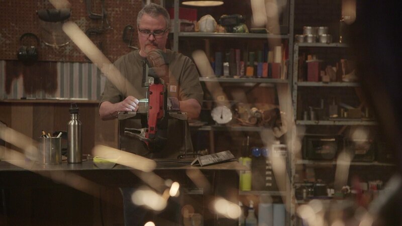 Sparks out of focus in foreground. J in background cutting metal on bandsaw – Bild: A&E Networks, LLC