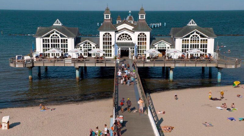 NDR Fernsehen DIE NORDSTORY SPEZIAL – KARIBIK VOR DER HAUSTÜR, „Die schönsten Ostseebäder in MV“, am Sonntag (25.10.20) um 20:15 Uhr. Die Seebrücke von Sellin, auf der Insel Rügen, gilt als die schönste des Landes. Ein „Traumschloss am Meer“. Mit einer feinen Gastronomie und Festsälen für zahlreiche Veranstaltungen, vor allem Hochzeiten. Die geschützte Bucht mit flachem Wasser ist vor allem bei Familien sehr beliebt. – Bild: NDR