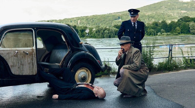 RHEINPROMENADE – Otto John (Sebastian Blomberg, r. vorne) bestätigt Dienstleiter Gülzow (Jens-Peter Fiedler, r. hinten), dass die Leiche sein Fahrer Manfred (Moritz Fischer, liegend) ist. – Bild: ZDF und ARD/​Odeon Fiction/​Kai Schulz