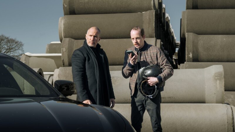 Lothar Lessen (Benno Fürmann, l.) besucht Gunnar Tiefenbach (Merlin Sandmeyer, r.) in dessen Zementwerk, als ein unbekannter Anrufer eine Geldforderung ausspricht. Lessen will sich um das Problem „kümmern“. – Bild: ZDF