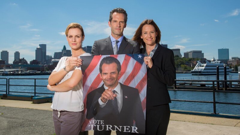 Mit Unterstützung seiner Frau Julie (Regula Grauwiller, r.) und der Pressefrau Robin Jennings (Anja Nejarri, l.) wird Eric Turner (Martin Rapold, M.) als Kongresskandidat aufgestellt. – Bild: ZDF