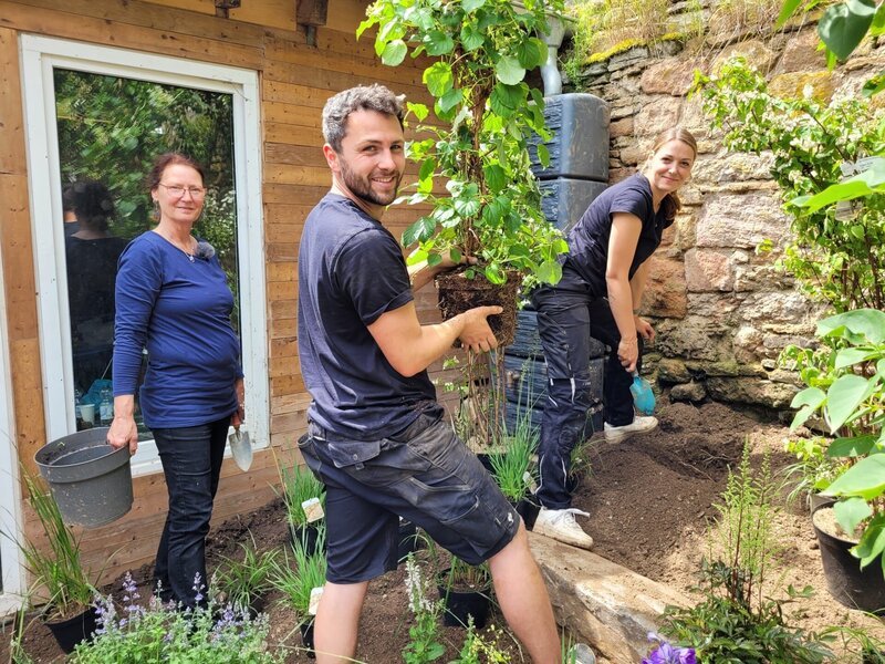 Mara Peters (r.) wohnt mit ihrem Partner Kevin (M.) und ihrer Mutter Petra (l.) auf einem 200 Jahre alten Vierkanthof. Gemeinsam wollen sie den Innenhof in einen gemütlichen Garten verwandeln. Frank Riese und Sebastian Burggraf haben Konzepte entwickelt, doch den Umbau macht die Familie selbst. – Bild: Gunther Weber /​ ZDF