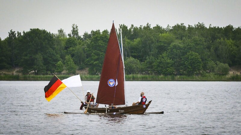 Ein asiatisches Fischerboot auf dem Bergwitzsee. Da staunen die einheimischen Segler vom Verein „Klar zur Wende“ und helfen Frank, das Auslegerboot zu Wasser zu lassen. Frank hat das Holzboot geschenkt bekommen und will jetzt das Segeln lernen. – Bild: MDR/​timeline