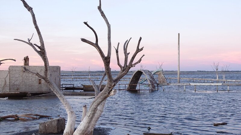 Das Schwimmbad von Epecuén. Heute ragen nur noch ein alter Baum und der Rest eines Sprungturms aus dem Wasser, nach dem eine Flut den Ort überspült hat. – Bild: ZDF
