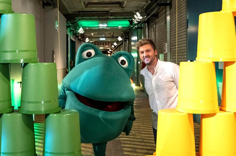 Bereit für den Wettkampf um den goldenen Tigerenten-Pokal: Moderator Johannes Zenglein und Maskottchen Günter Kastenfrosch. – Bild: SWR/​Patricia Neligan