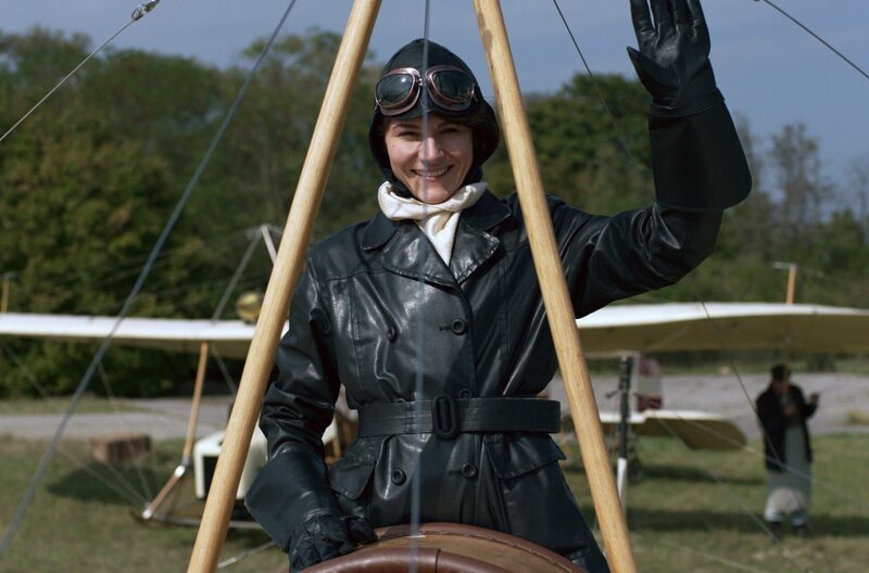 Melli Beese (Lilith Häßle) nimmt als Pilotin an Flugshows teil und wird vom Publikum für ihre Flugkünste gefeiert. (Spielszene) – Bild: NDR /​ Metafilm