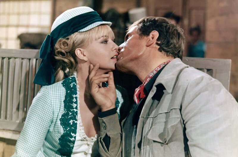 Die schöne Connie Breastfull (Sophie Daumier) und Gary Tampeko (Giuliano Gemma) kommen sich näher, während sie auf die Kutsche warten. – Bild: Les Productions J. Roitfeld Die schöne Connie Breastfull (Sophie Daumier) und Gary Tampeko (Giuliano Gemma) kommen sich näher, während sie auf die Kutsche warten. – Bild: Les Productions J. Roitfeld