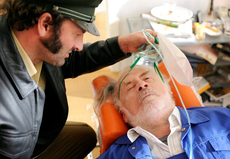 Der Huber Fred (Max Schmidt, l.) erkennt den Alfons Berger (Fred Stillkraut, r.) und zieht ihm die Beatmungsmaske vom Gesicht. – Bild: BR/​ARD/​Barbara Bauriedl